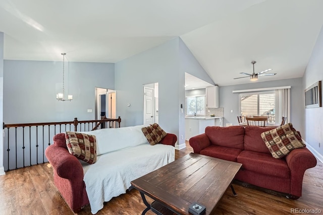 living room with vaulted ceiling, ceiling fan with notable chandelier, and wood-type flooring