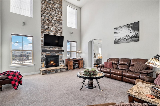 carpeted living room with a fireplace and a towering ceiling