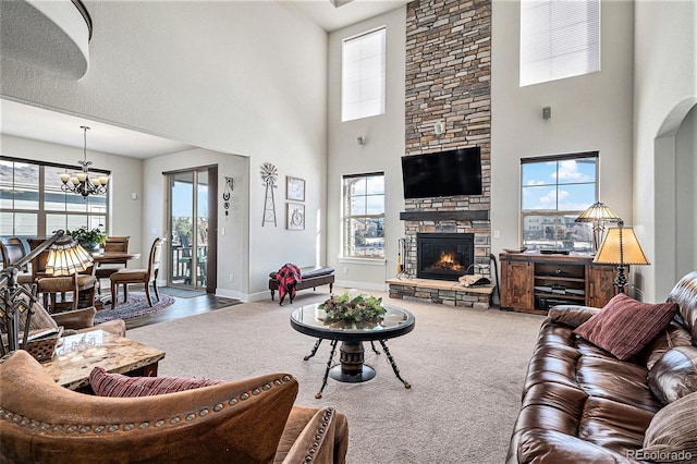 carpeted living room featuring a fireplace, a high ceiling, and a notable chandelier