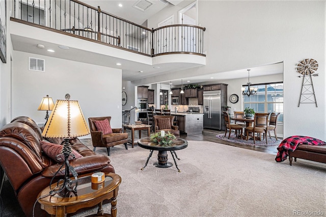 carpeted living room featuring a chandelier and a towering ceiling