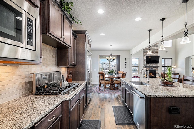 kitchen with decorative backsplash, sink, a kitchen island with sink, stainless steel appliances, and dark brown cabinets