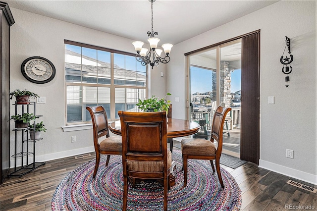 dining space featuring dark wood-type flooring and a notable chandelier