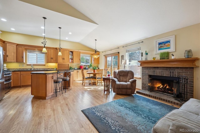 living area with lofted ceiling, light wood finished floors, a fireplace, and a healthy amount of sunlight