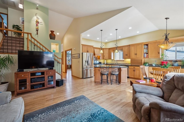 living room featuring recessed lighting, visible vents, light wood-style floors, high vaulted ceiling, and stairs