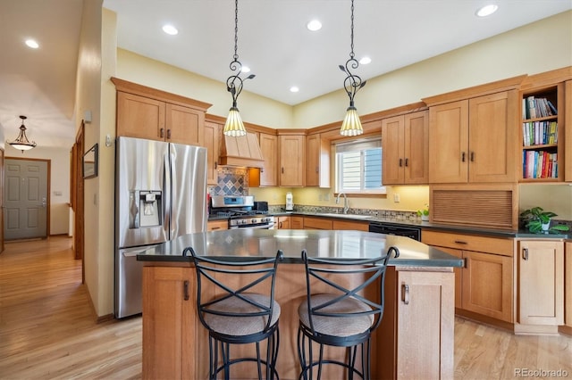 kitchen featuring dark countertops, a center island, stainless steel appliances, light wood-type flooring, and a sink