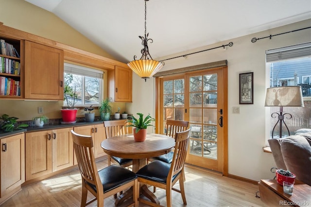 dining space with vaulted ceiling, baseboards, and light wood-style floors