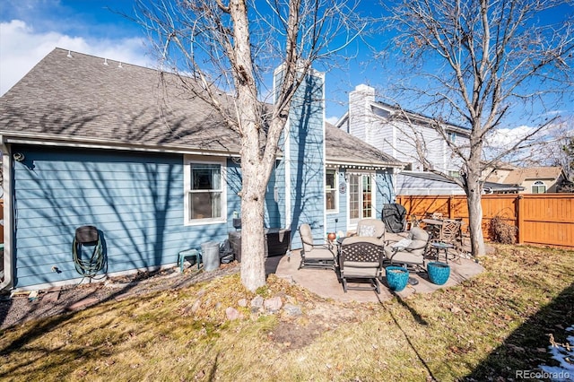 rear view of house featuring a patio area, fence, a chimney, and roof with shingles