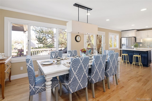 dining area with light wood-type flooring, baseboards, and ornamental molding