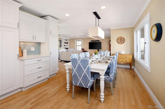 dining space featuring light wood finished floors, recessed lighting, crown molding, and baseboards