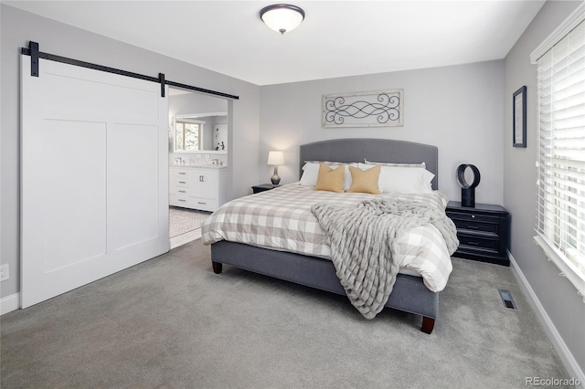 bedroom with a barn door, multiple windows, and carpet flooring