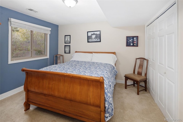 bedroom with baseboards, visible vents, a closet, and light carpet