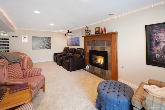 living room with a tiled fireplace, visible vents, baseboards, and carpet