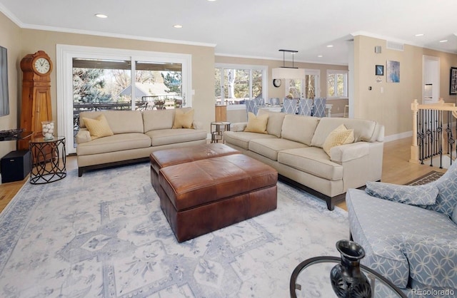 living area featuring visible vents, light wood-style floors, baseboards, and ornamental molding