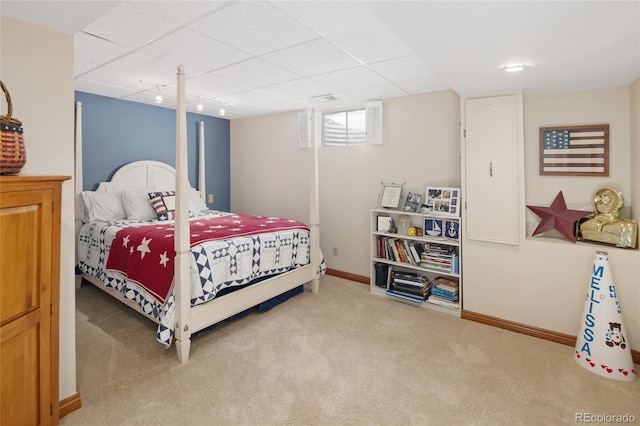 bedroom with a drop ceiling, baseboards, and carpet floors