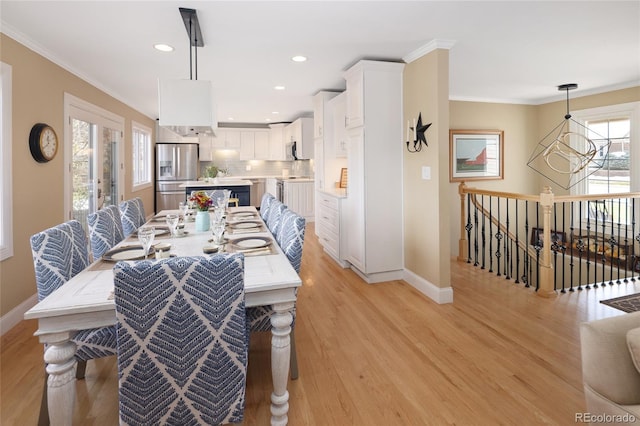 dining space featuring light wood-type flooring, baseboards, a chandelier, and crown molding