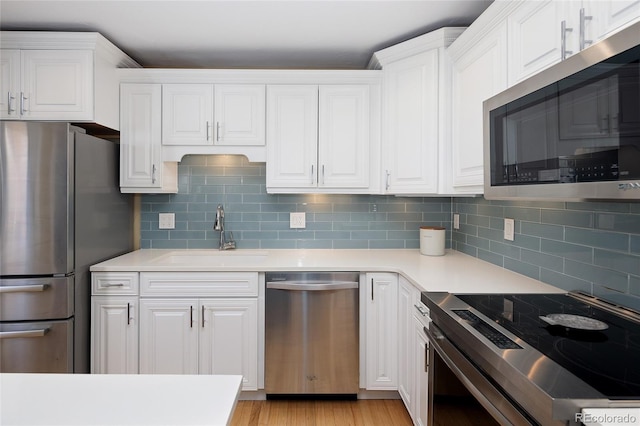 kitchen with a sink, stainless steel appliances, white cabinets, and light countertops