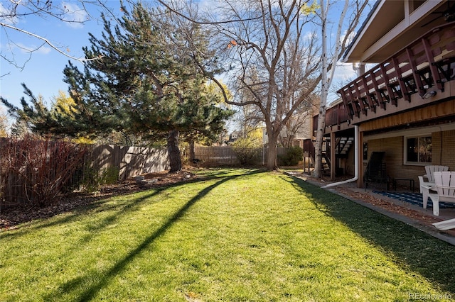 view of yard with a patio, a fenced backyard, and stairs