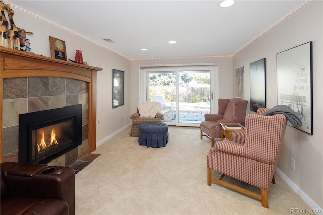 living room featuring baseboards, light carpet, and a tiled fireplace