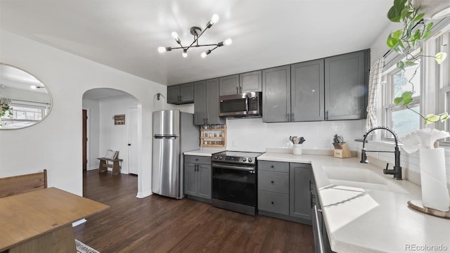 kitchen featuring sink, dark hardwood / wood-style flooring, a chandelier, gray cabinetry, and appliances with stainless steel finishes