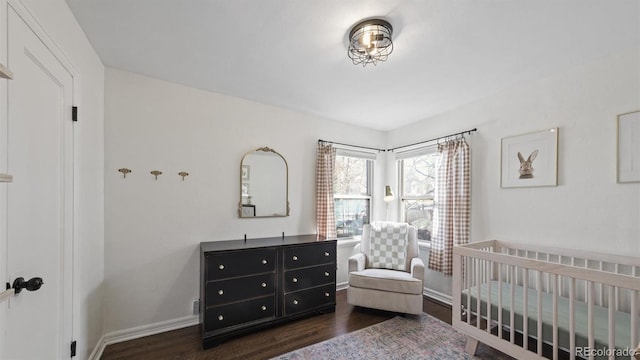 bedroom with dark wood-type flooring and a nursery area