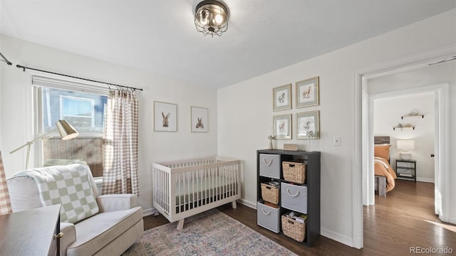 bedroom featuring a nursery area and dark wood-type flooring