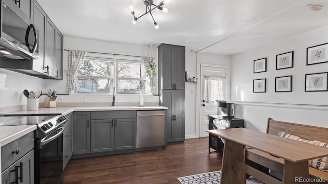 kitchen with sink, gray cabinets, dark hardwood / wood-style flooring, a notable chandelier, and appliances with stainless steel finishes