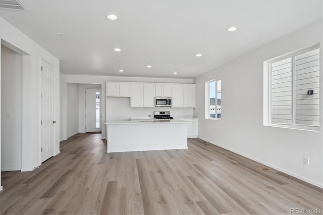 kitchen featuring a center island with sink, light wood-type flooring, white cabinetry, and stainless steel appliances