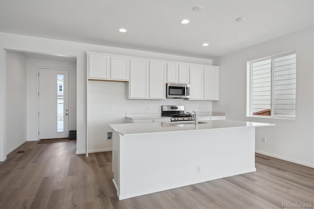 kitchen with white cabinets, sink, stainless steel appliances, and a kitchen island with sink