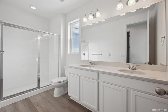 bathroom featuring hardwood / wood-style flooring, vanity, toilet, and a shower with shower door