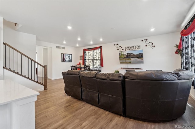 living area with wood finished floors, recessed lighting, stairs, and baseboards