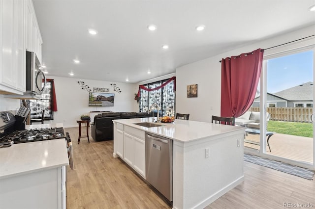 kitchen with appliances with stainless steel finishes, white cabinetry, a sink, light countertops, and recessed lighting