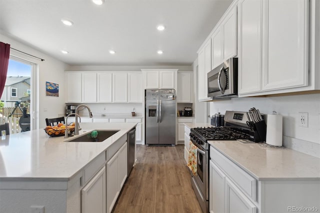 kitchen featuring stainless steel appliances, a sink, recessed lighting, white cabinetry, and light wood-type flooring