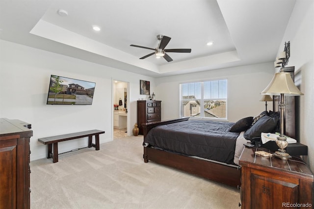 bedroom with a tray ceiling, light carpet, baseboards, recessed lighting, and connected bathroom