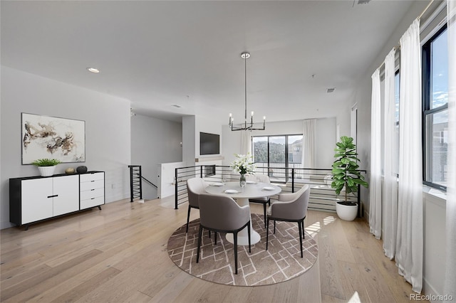 dining area with light hardwood / wood-style flooring and a notable chandelier