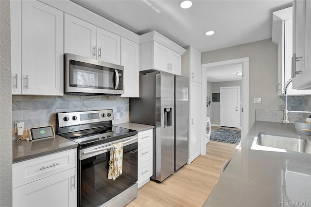 kitchen featuring backsplash, light wood-type flooring, white cabinets, and appliances with stainless steel finishes