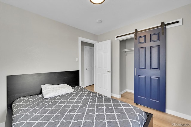 unfurnished bedroom featuring a barn door, hardwood / wood-style flooring, and a closet