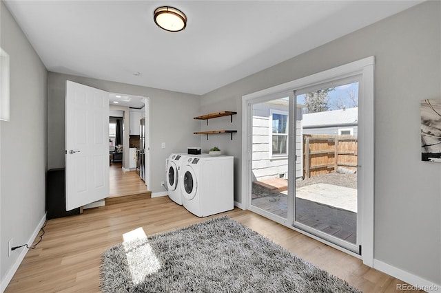 laundry area with washing machine and clothes dryer and light hardwood / wood-style flooring