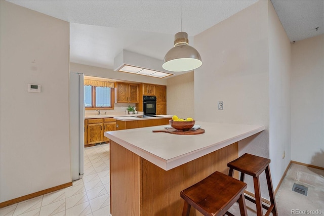 31 Irene Ct, Broomfield, CO 80020 - kitchen featuring black appliances, brown cabinetry, baseboards, light countertops, and a breakfast bar