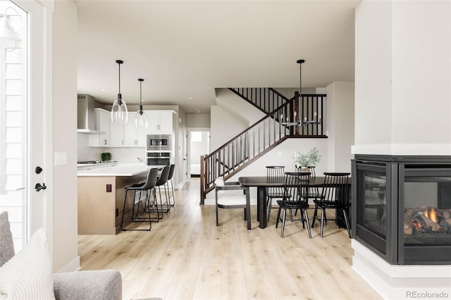 living area featuring stairway, light wood finished floors, baseboards, and recessed lighting