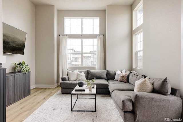 living area with a towering ceiling, wood finished floors, and baseboards