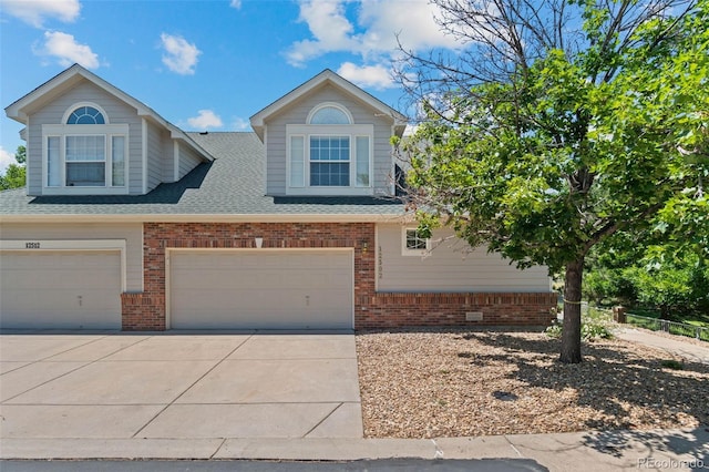 12502 E Harvard Cir, Aurora, CO 80014 - view of front of property with a garage, brick siding, a shingled roof, and driveway