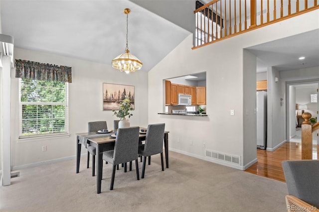 12502 E Harvard Cir, Aurora, CO 80014 - dining area featuring high vaulted ceiling, a chandelier, and light carpet