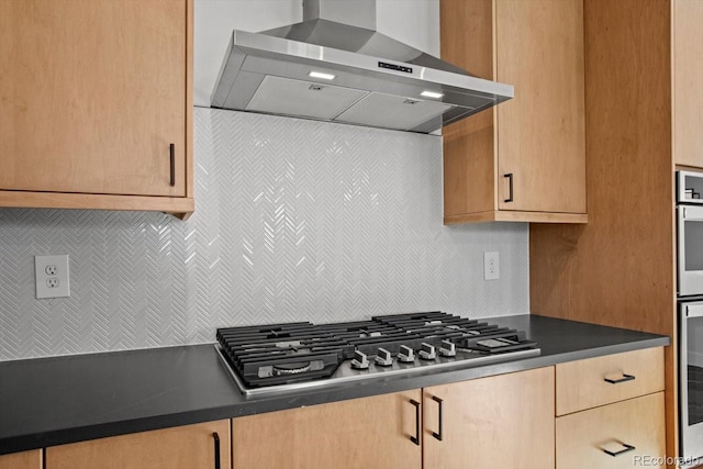 kitchen featuring wall chimney range hood, decorative backsplash, and stainless steel appliances