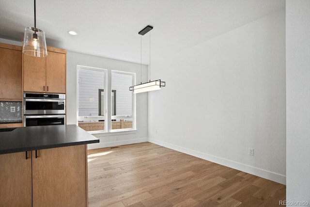 kitchen with decorative light fixtures, light hardwood / wood-style floors, and stainless steel double oven