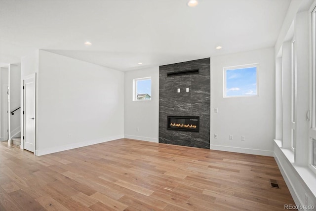 unfurnished living room with a tiled fireplace and light hardwood / wood-style floors