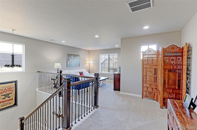 corridor with a textured ceiling and light colored carpet