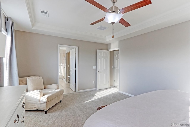 bedroom with a tray ceiling, ceiling fan, connected bathroom, ornamental molding, and light colored carpet