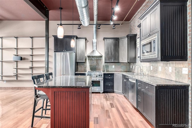 210 W Magnolia St Unit 360, Fort Collins, CO 80521 - kitchen featuring premium appliances, a sink, light wood finished floors, wall chimney range hood, and a kitchen bar