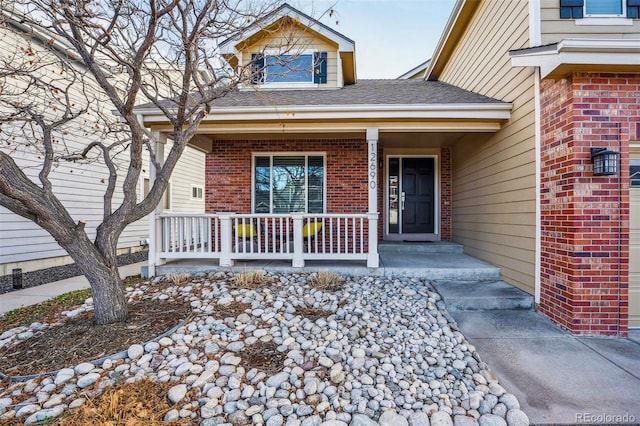 entrance to property featuring covered porch and brick siding