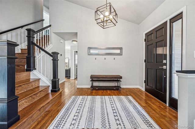 foyer featuring stairs, vaulted ceiling, baseboards, and wood finished floors